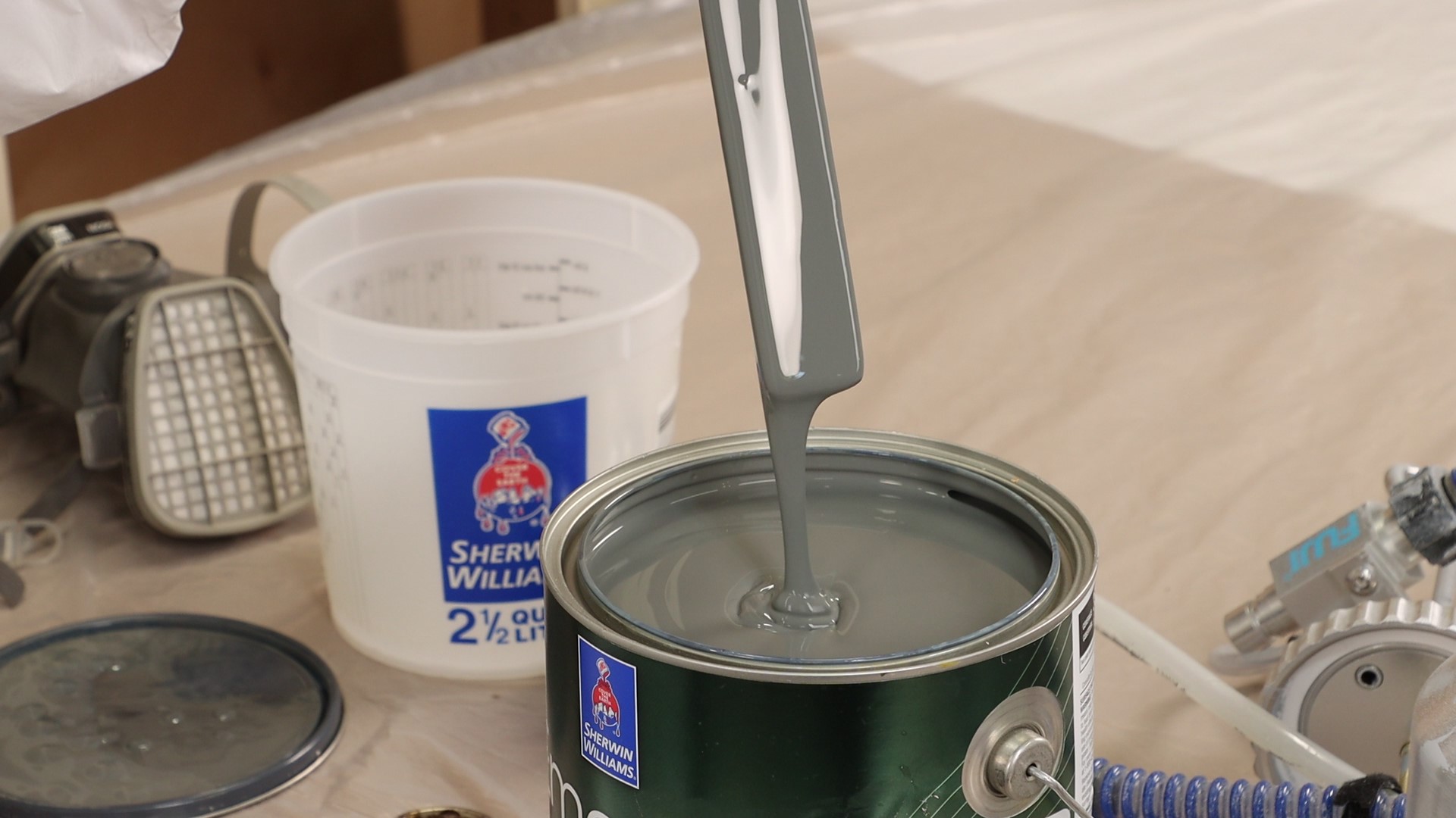 Dipping a paint stick in jar of paint